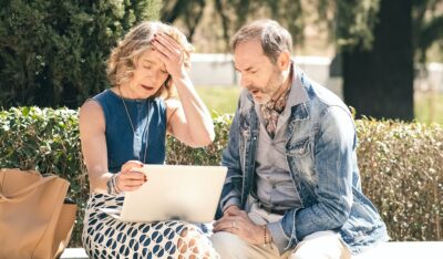 Senior couple looking sad and disappointed while using a laptop to detect fraud.